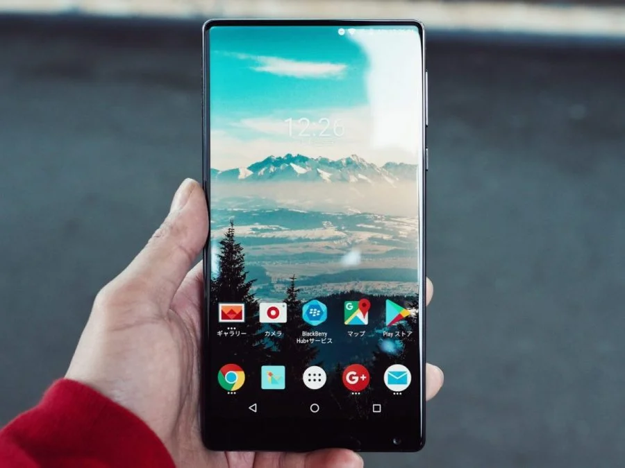 a person holding a phone with a mountain in the background